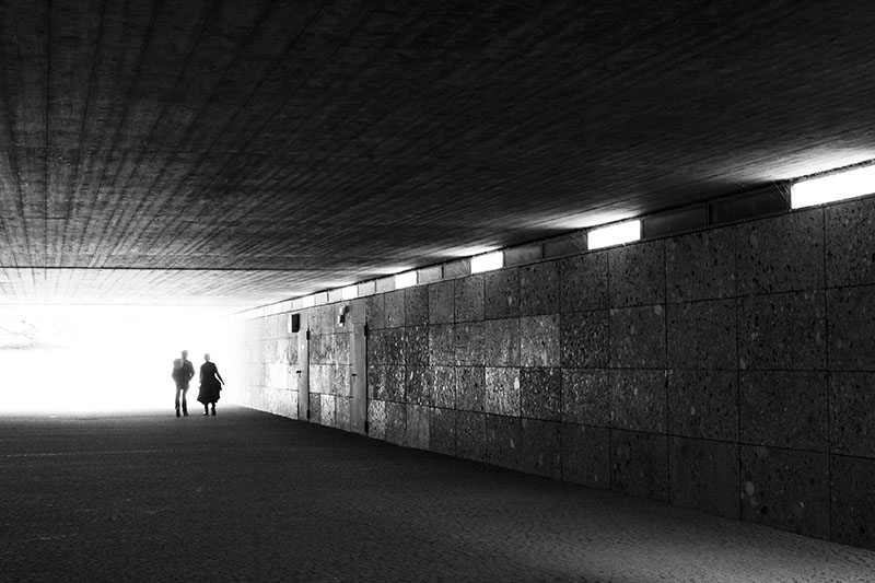 A sample of Rae's photography - two people walking under a rectangular tunnel